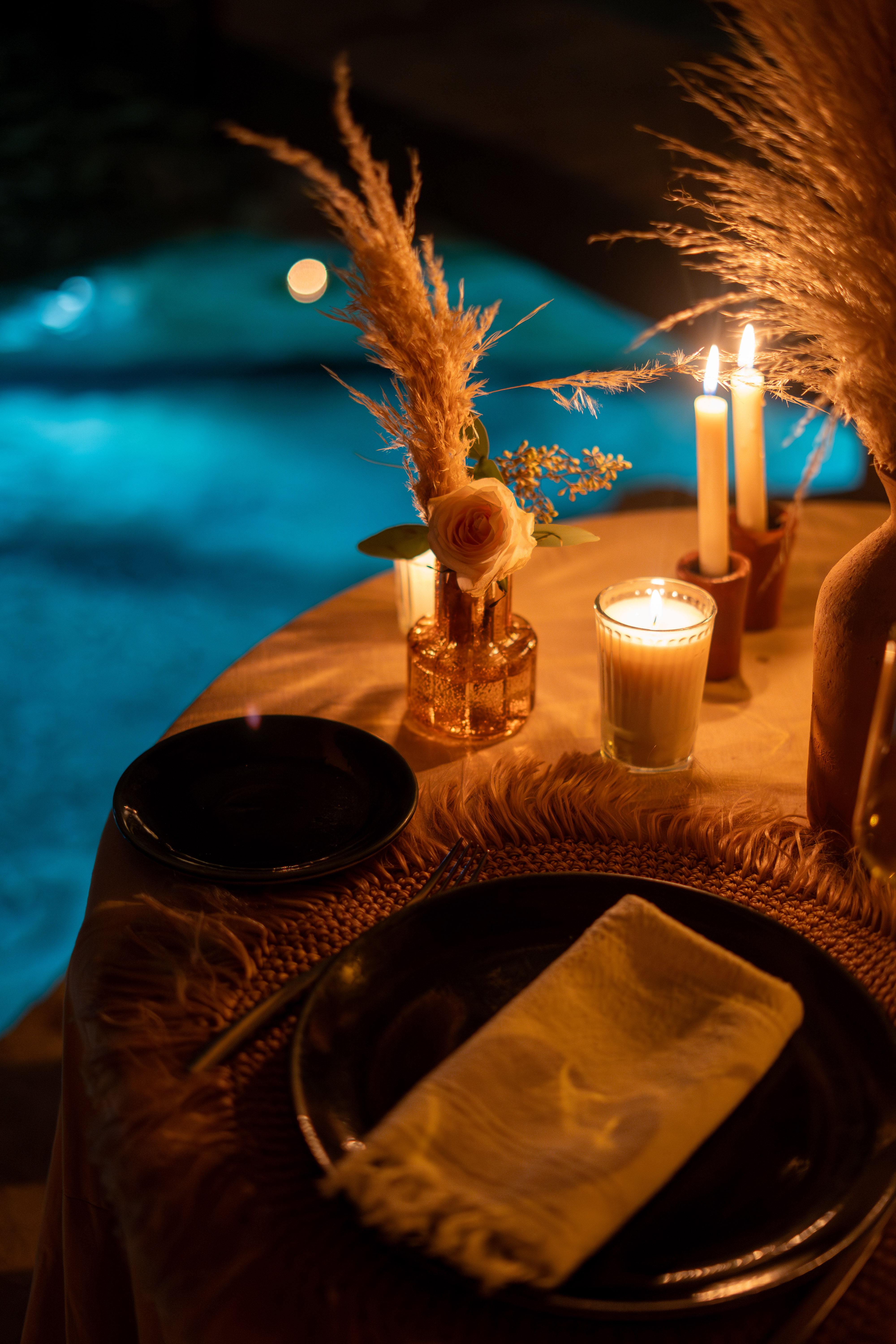 Mesa elegante con cena gourmet iluminada con velas junto a un cenote de noche